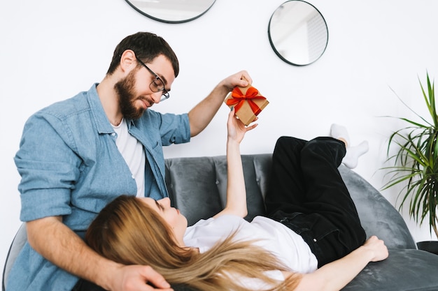 Mann überraschte ihre Freundin mit Geschenk, glückliches Paar, das Valentinstag oder Jahrestag feiert