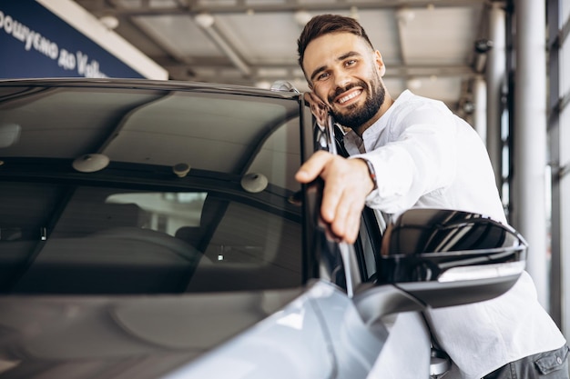 Mann umarmt ein neues Auto in einem Autohaus