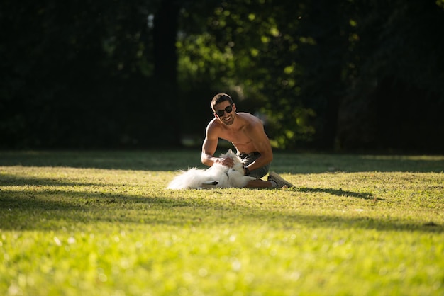 Mann und deutscher Spitz sitzen zusammen im Park und genießen die Aussicht beim Herumspielen