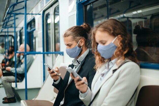 Mann und eine Frau mit Smartphones sitzen in einem U-Bahnwagen