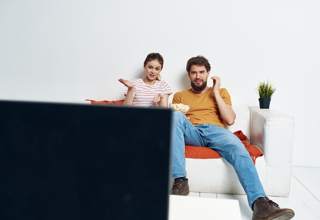 Mann und Frau auf der Couch vor dem Fernseher, Blumen eingetopft