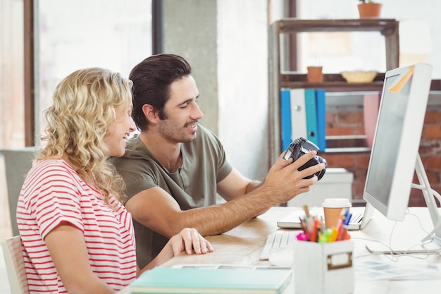 Mann und Frau, die Digitalkamera im Büro betrachten