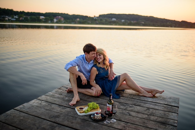 Mann und Frau, die ein Picknick auf dem Pier nahe dem See haben.