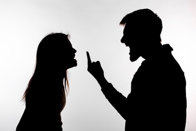 Foto mann und frau, die häusliche gewalt in der studio-silhouette ausdrücken