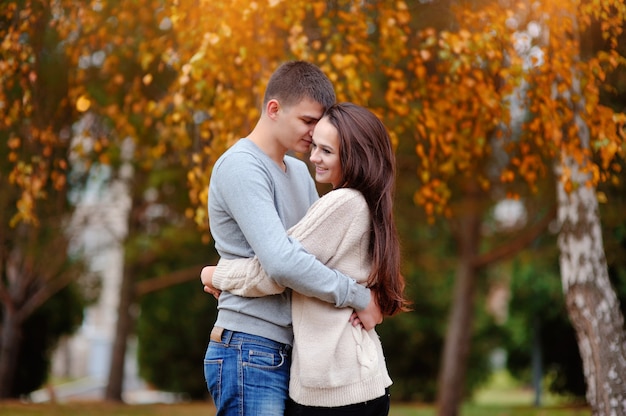 Mann und Frau, die im Herbstpark umfassen