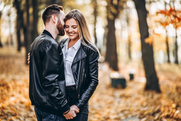 Mann und Frau, die im Hintergrund des Herbstparks umarmen und lächeln.