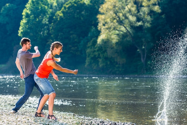 Mann und Frau, die Steine auf Fluss gleiten