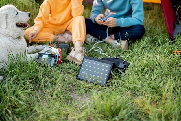 Mann und frau, die während der reise telefone mit solarpanel aufladen