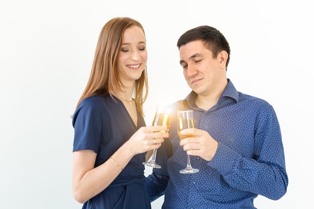 Mann und Frau, die Weihnachts- oder Silvesterparty mit Gläsern Champagner auf weißem Hintergrund feiern.