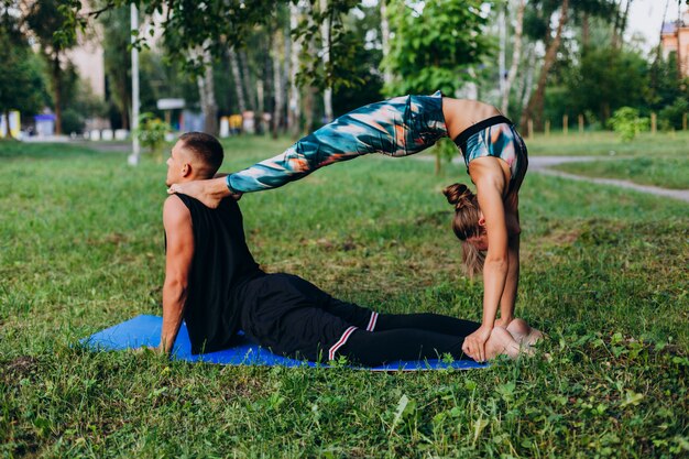 Mann und Frau, die zusammen Yoga im Park im Freien tun. Mann, der eine Frau küsst