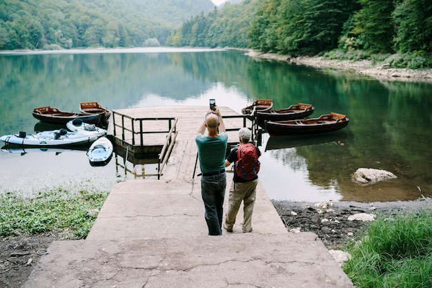 Mann und Frau fotografieren Boote am Pier am Pragser See, Italien