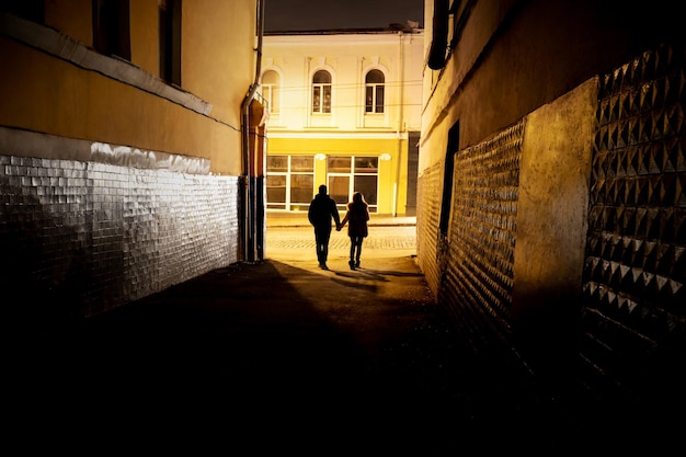 Mann und Frau gehen Händchen haltend aus der dunklen Gasse ins Licht