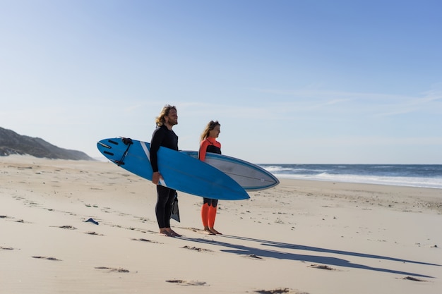 Mann und Frau gehen mit Surfbrettern zum Meer. Mann und Mädchen gehen surfen