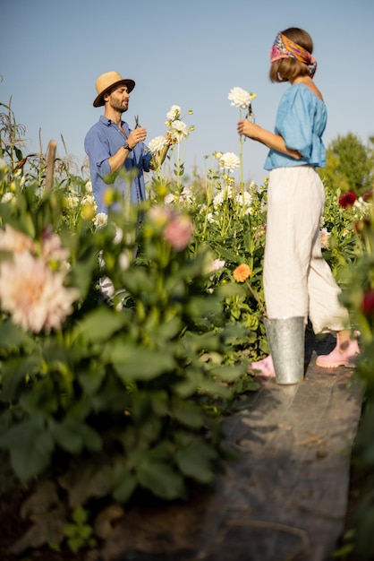 Mann und Frau holen Blumen auf dem Bauernhof im Freien ab