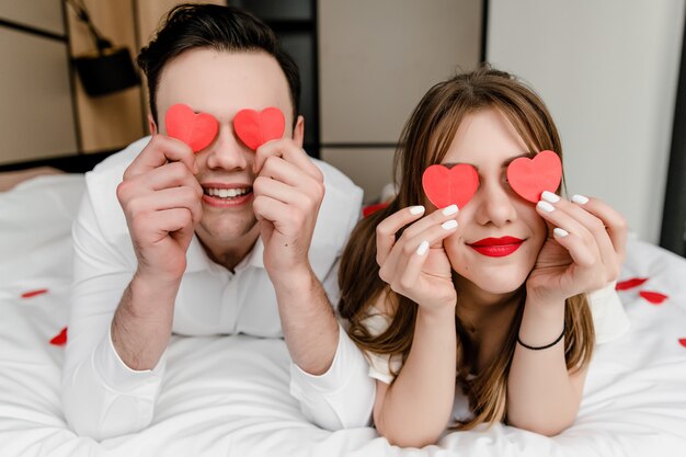 Mann und Frau im Bett mit Herzform in den Händen