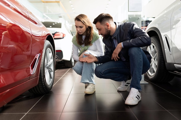 Mann und Frau inspizieren ein neues Auto vor dem Kauf in einem Autohaus