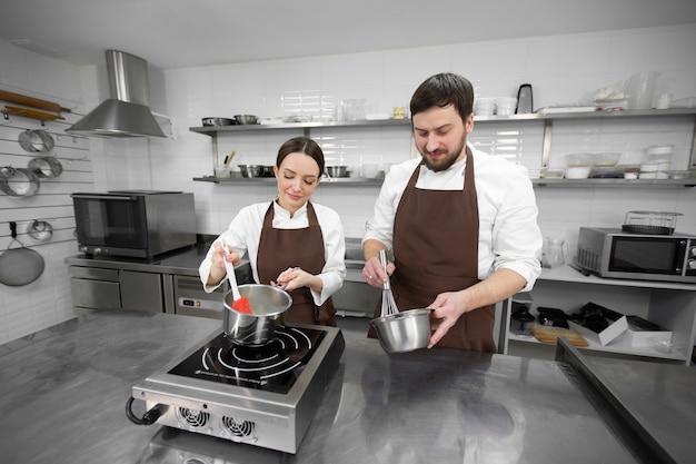 Mann und Frau Konditor bereiten Dessert gemeinsam in einer professionellen Küche zu