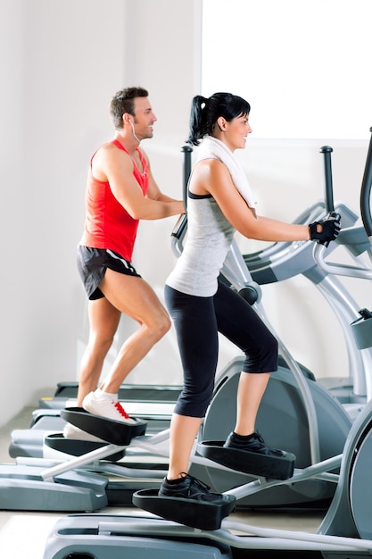 Mann und Frau mit Ellipsentrainer im Fitnessstudio