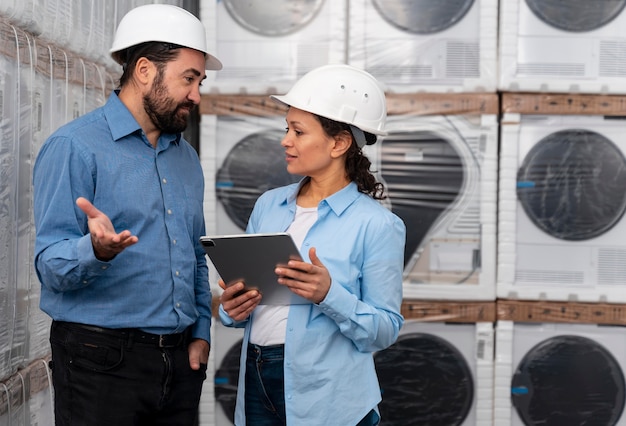 Mann und Frau mit Helm, der im Lager arbeitet