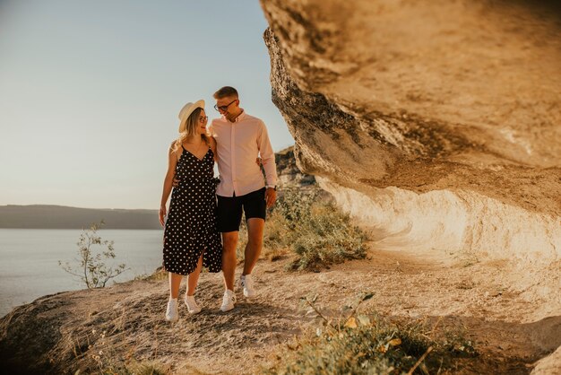 Mann und Frau mit Hut gehen die Felsen über der Klippe entlang.