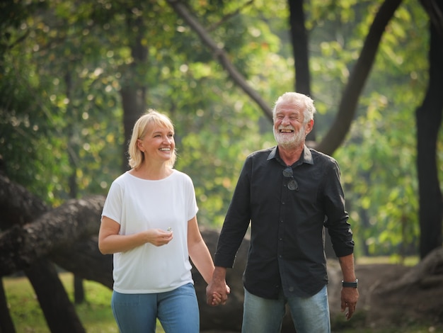 Mann und Frau mit zwei glücklichen Senioren gehen und sprechen im Park