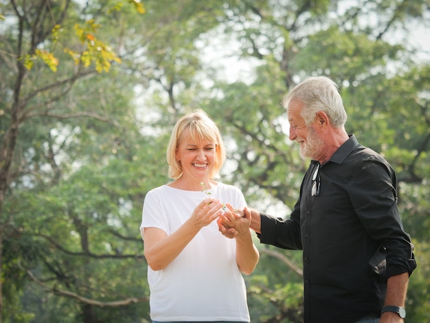 Mann und Frau mit zwei glücklichen Senioren gehen und sprechen im Park