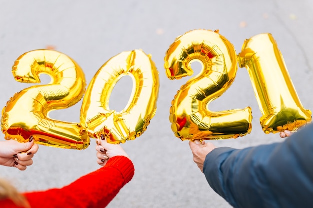 Mann und Frau paar Hände halten Goldfolienballons Ziffer 2021. Neujahrsfeierkonzept.