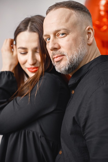 Mann und Frau posieren im Studio in der Nähe eines herzförmigen roten Ballons