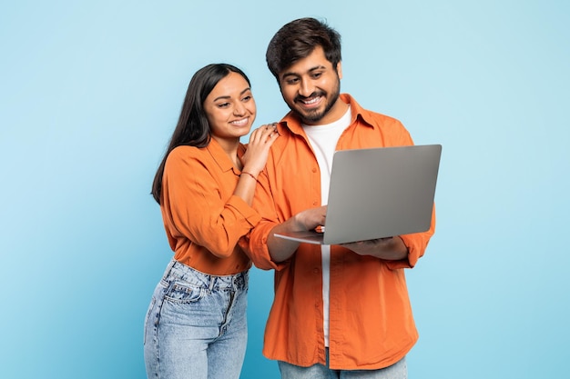 Mann und Frau schauen auf den Laptop auf blau