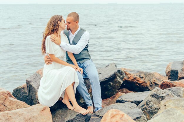 Mann und Frau sitzen auf den Felsen am Meer