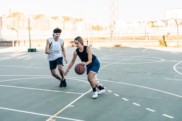 Mann und Frau spielen Basketball bei Sonnenuntergang in einem städtischen Gericht