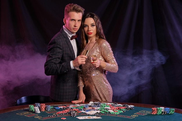 Mann und Frau spielen Poker im Casino und feiern den Sieg am Tisch mit Stapeln von Chips Geldkarten Cham