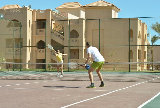 Mann und Frau spielen Tennis am Hof