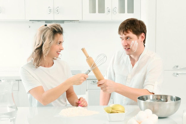 Mann und Frau streiten sich in der Küche beim Kochen Komische und fröhliche Konfrontation zwischen Mann und Frau im Küchenhintergrund