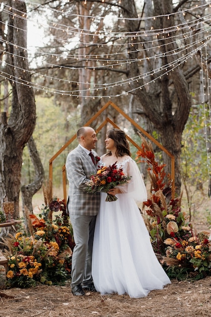 Mann und Frau verlobten sich im Herbstwald bei einer geschmückten Hochzeitszeremonie
