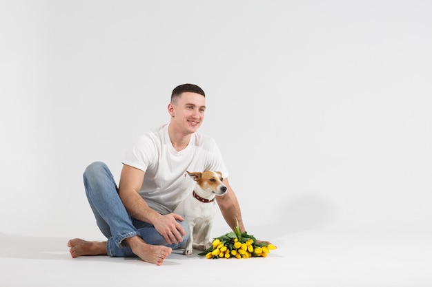 Mann und Hund mit Blumen sitzen auf dem Boden.