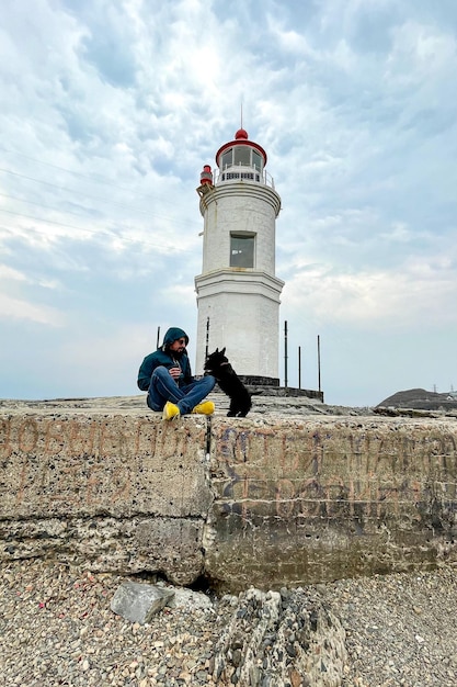 Mann und Hund spielen in der Nähe des Leuchtturms