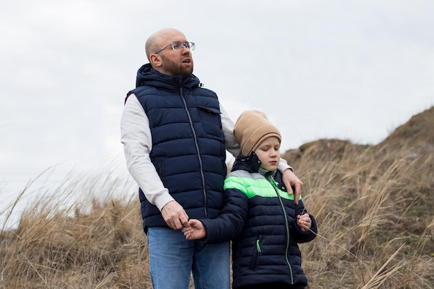 Mann und Junge, Vater und Sohn stehen Seite an Seite und umarmen sich auf dem Hintergrund des grauen Himmels, Nebelatmosphäre