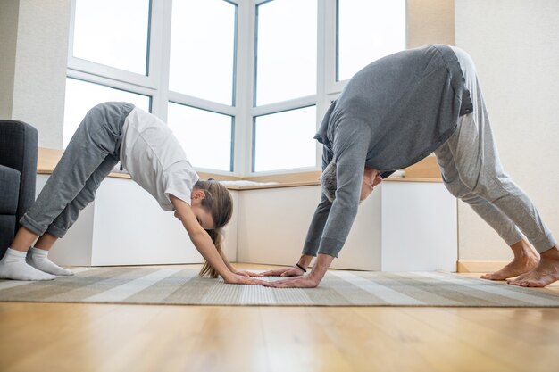 Mann und Mädchen in Hauskleidung beim Yoga