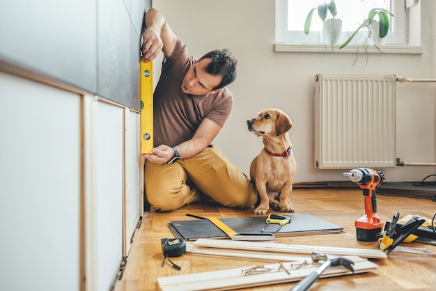 Mann und sein Hund, die zu Hause Erneuerungsarbeiten erledigen