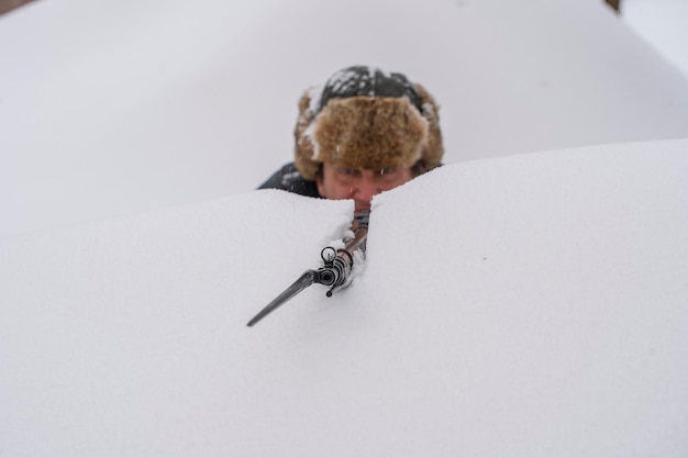 Mann und sowjetisches Mosin-Gewehr mit einem Bajonett in einem verschneiten Graben im Winter