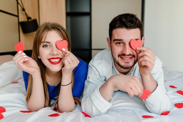 Mann und verliebte Frau im Bett mit Herzformen