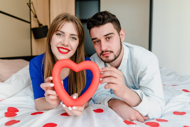 Mann und verliebte Frau im Bett mit Herzformen