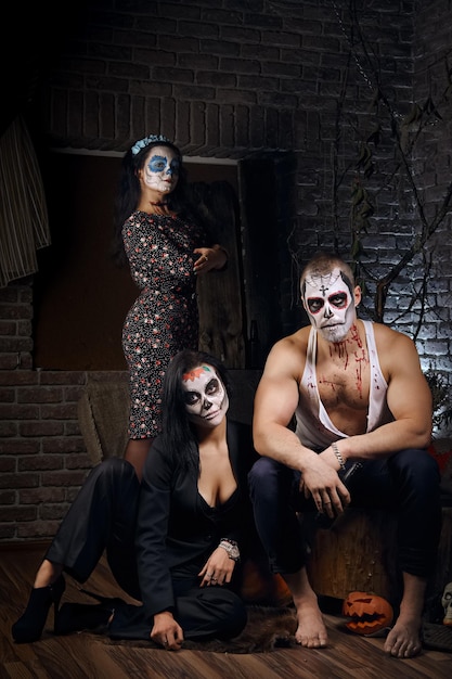 Mann und zwei Frauen mit Sugar Skull Make-up in Halloween-Dekoration