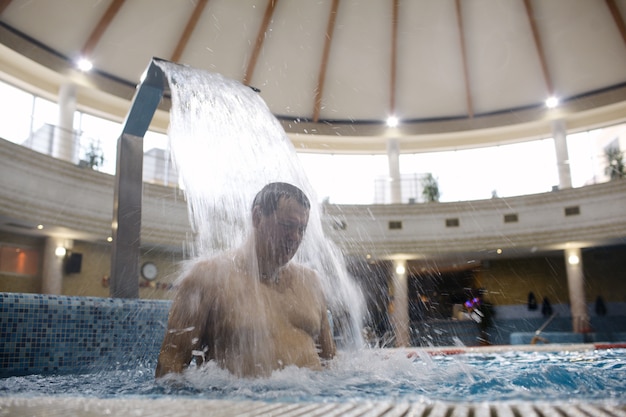 Mann unter Wasserstrom im Swimmingpool