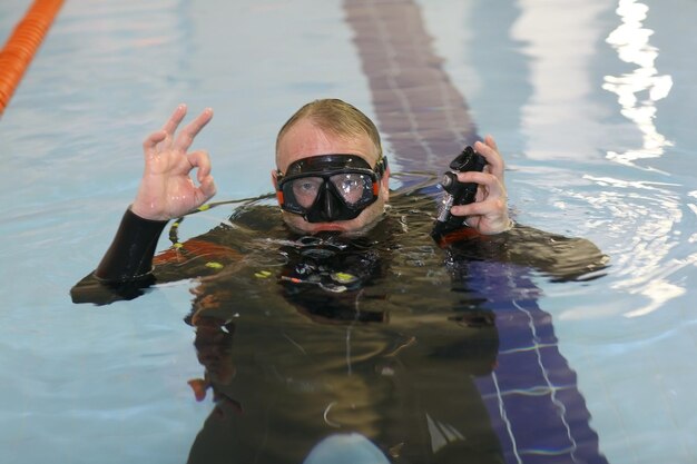 Mann unterrichtet Tauchen im Pool, Schwimmtrainer