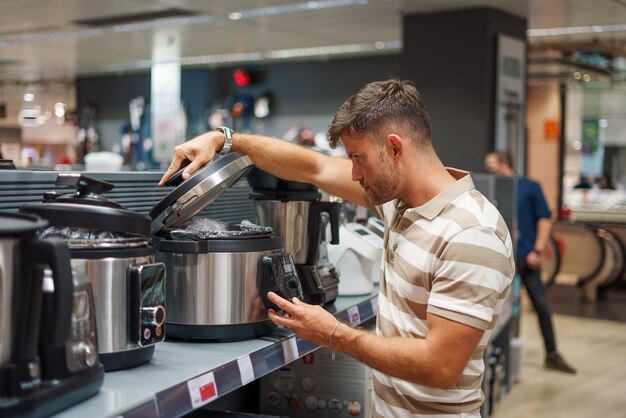 Mann untersucht Multikocher im Laden