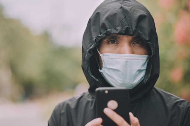 Mann verwenden medizinische Gesichtsmaske und spielen auf dem mobilen Smartphone