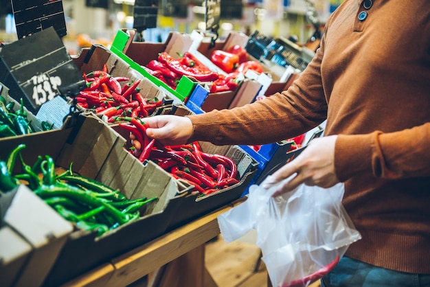 Mann wählt rote Paprika im Markt. Einkaufskonzept