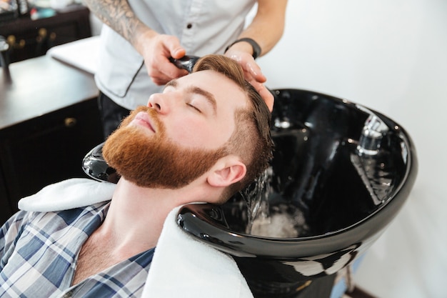 Mann wäscht den Kopf zum Kunden im Friseursalon